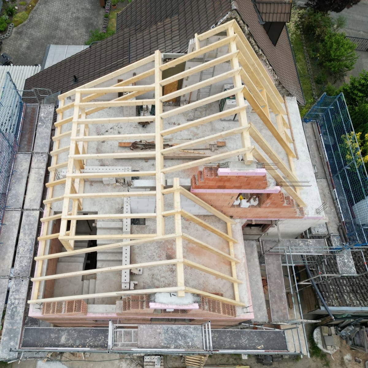 Baustelle mit neuem Holz-Dachstuhl und Gerüst, bereit für die Dacheindeckung
