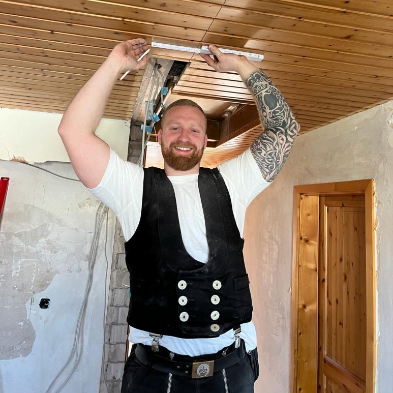 Zimmerer bei Deckenarbeiten: Handwerker misst Öffnung in Holzdecke aus – traditionelles Handwerk und moderner Holzbau bei Sanierung.