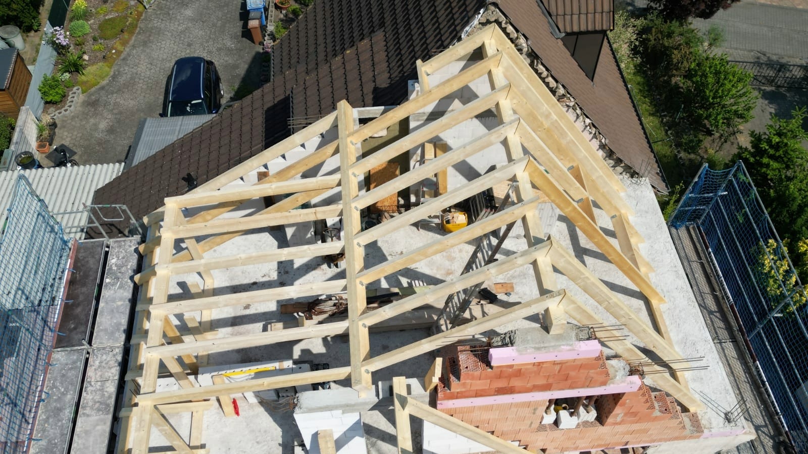 Baustelle mit neuem Holz-Dachstuhl und Gerüst, bereit für die Dacheindeckung